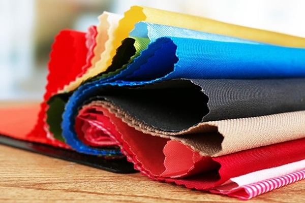 Stapel kleurige stoffen. Illustratie bij IMVO Convenant Duurzame Kleding en Textiel.