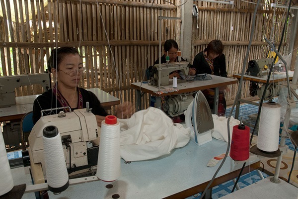 Vrouwen aan het werk achter hun naaimachines in grote fabriek. Illustratie bij IMVO Convenant Duurzame Kleding en Textiel.