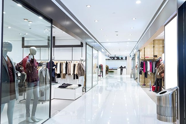 Gang in een modern winkelcentrum met diverse kledingwinkels. Illustratie bij IMVO Convenant Duurzame Kleding en Textiel.