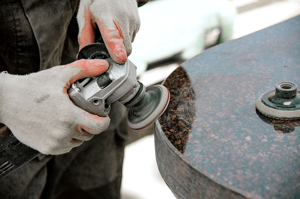 Een man werkt aan het polijsten van een marmeren steen met een haakse slijper.
