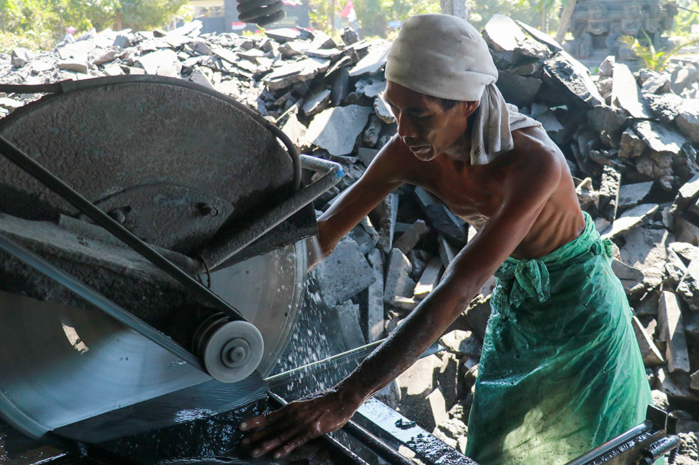 Een man snijdt een zwarte vulkanische steen met een waterstraalsnijmachine, Bali, Indonesië