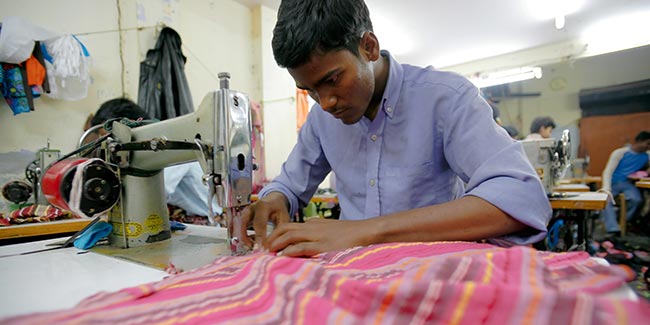 Man aan het werk achter zijn naaimachine in kleine fabriek. Illustratie bij IMVO Convenant Duurzame Kleding en Textiel.